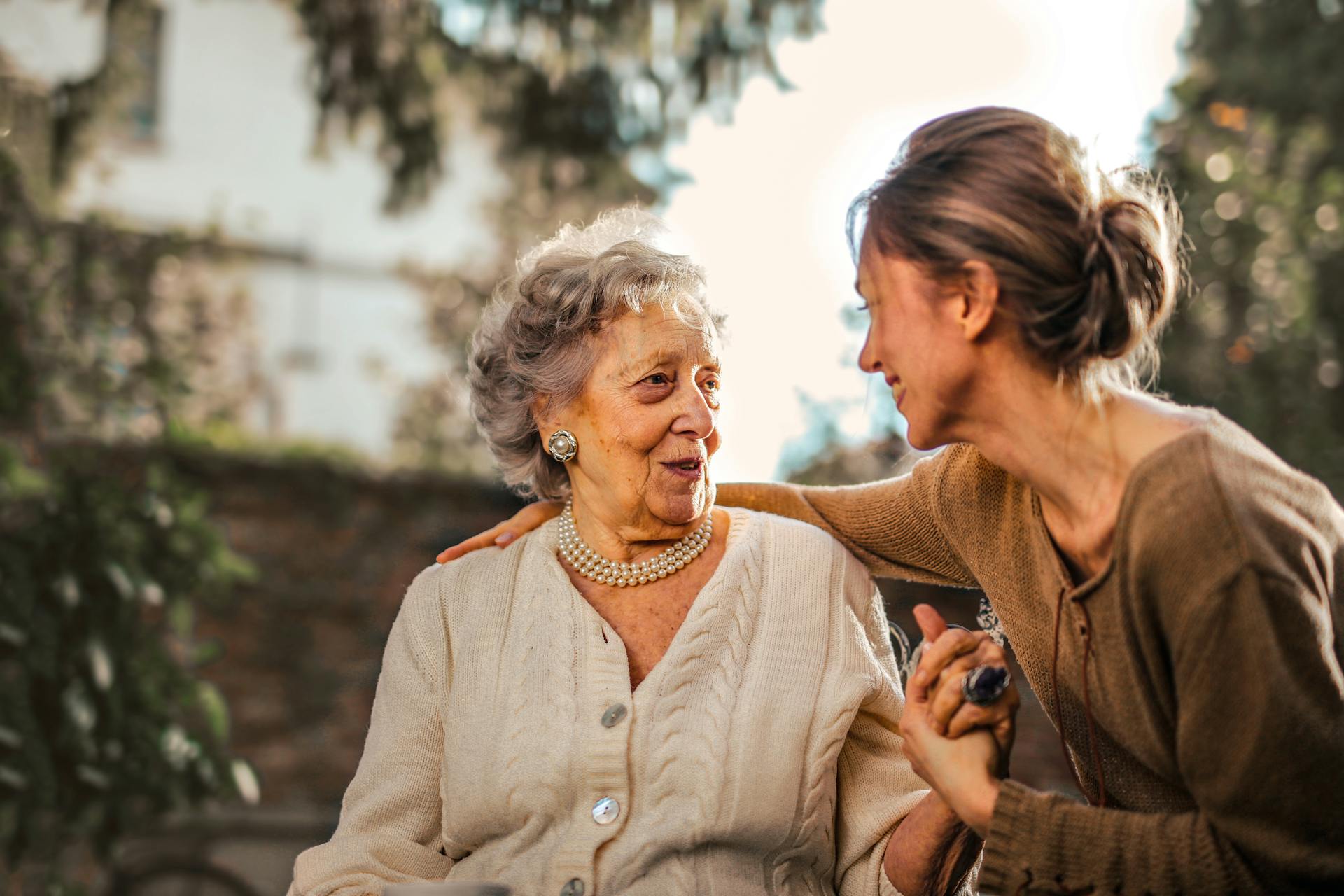 An older woman and her companion sharing a warm, attentive moment together outdoors